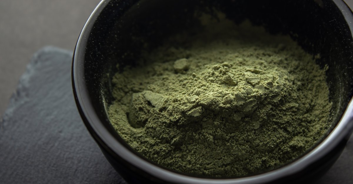 Close-up of green, powdered kief in a black container. Most of the powder is toward the front of the jar.